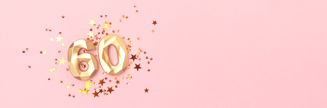 Banner with gold colored number sixty and stars confetti on a pink background. Creative concept with copy space.