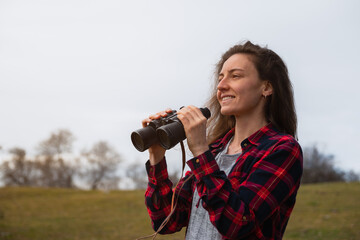 Young woman holding binoculars on her hands and smiling for what she just saw