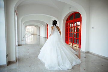 A girl in a magnificent wedding dress, runs in a snow-white registry office.