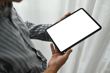Young working man standing in office and using digital tablet. White empty screen for graphic display montage