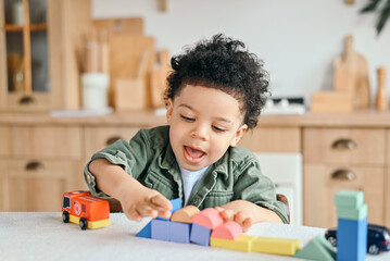 Happy little african american boy with bushy curly hair playing with colorful wooden blocks,...