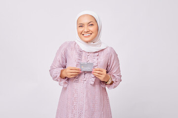 Excited young Asian Muslim woman wearing hijab and purple dress received approval to accept credit cards isolated on white studio background