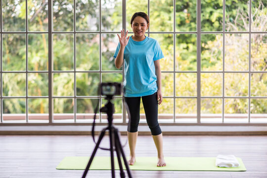 Asian fitness trainer raise hand to say hi or hello to online yoga class