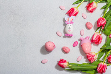 Pink tulips with Easter eggs on light stone concrete background. Festive concept, greeting card