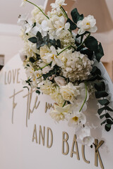Arch decorated with flowers, and greenery with the text love you to the moon and back. Wedding reception for the luxury ceremony. Trendy decor party in the banquet area. Photo-wall white.