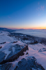 雪に覆われた斜面の下に雲海が広がる冬の夜明け。日本の北海道の美幌峠の風景