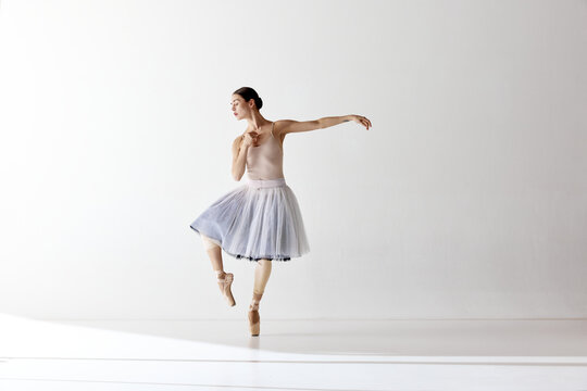Beautiful ballerina wearing tutu emotional dancing over white background