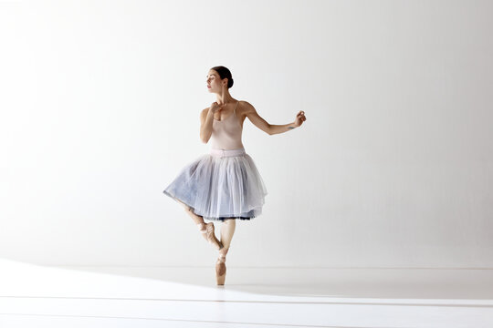 Inspired beautiful ballerina dancing and looking away over white background