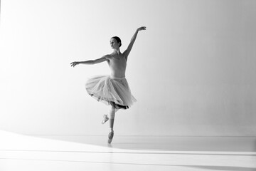 Monochrome. Young graceful ballerina posing in studio and demonstrating elegant movement