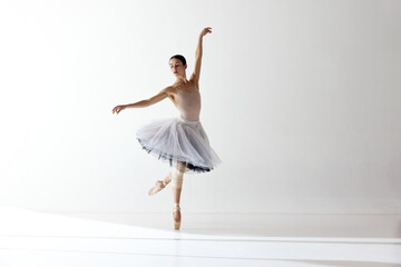 Shot of one adorable ballerina dancing with elegance hands over white background