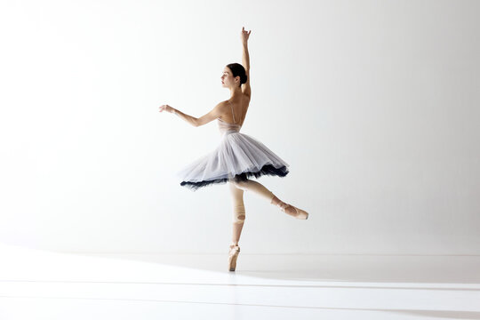 Ballerina wearing tutu dancing elegant movements over white background. Beauty of classical dance