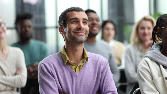 Young businessman sitting listening to trainer speaking to audience