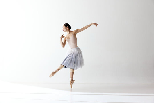 Beautiful woman ballet dancer dancing over white background