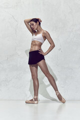 Upset young ballerina standing and looking away with closed eyes over white background © Lustre Art Group 