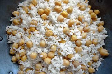 Close up view of white rice cooked with chickpeas inside an old iron skillet