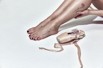 Cropped image of tired female legs, ballerina in pointe over white studio background. Close up © Lustre Art Group 
