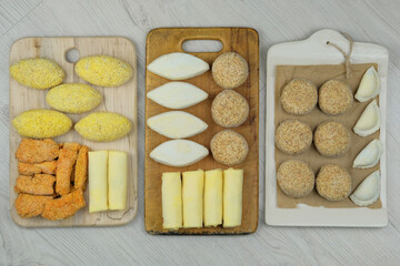 Assorted homemade semi-finished products on wooden boardes. Frozen cutlets, dumplings, nuggets. Preparations of homemade food.
