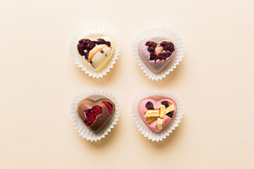 chocolate sweets in the form of a heart with fruits and nuts on a colored background. top view with space for text, holiday concept