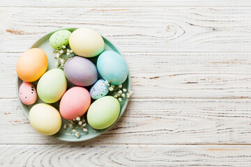 Happy Easter composition. Easter eggs in basket on colored table with gypsophila. Natural dyed colorful eggs background top view with copy space