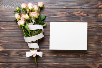 Greeting holiday card mockup with fresh roses on colored table background, mock up with copy space...
