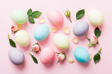 Happy Easter. Easter eggs on colored table with yellow roses. Natural dyed colorful eggs background top view with copy space