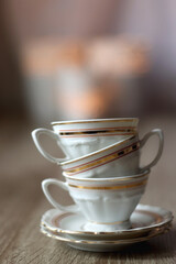 Vintage white teacups with gold details. Lit candles in the background. Selective focus.