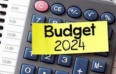 BUDGET 2024 text on a small yellow piece of paper lying on top of the calculator. Concept for...
