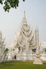 "Wat Rong Khun" Famous temple in chiangrai Thailand. Beautiful white temple with green field for travel landmark