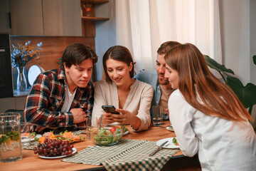 Using smartphone. Group of people are on the kitchen, having dinner, spending time together