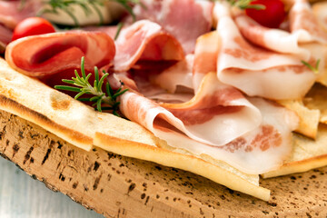 Vassoio di tipici salumi sardi con pane carasau, cibo italiano 