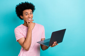 Photo of cheerful it specialist student worker guy wear pink t-shirt hold computer thoughtful intelligence isolated on cyan color background