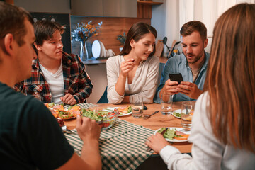 Delicious food. Group of people are on the kitchen, having dinner, spending time together