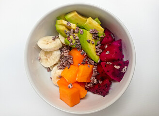a healthy breakfast bowl filled with papaya, banana, dragon fruit, avocado and a sprinkling of cacao nibs. 
