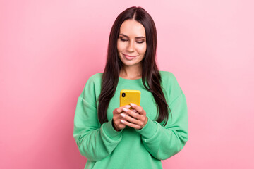 Photo of young youtube blogger attractive hispanic girl wear green jumper hold samsung phone reading last post isolated on pink color background