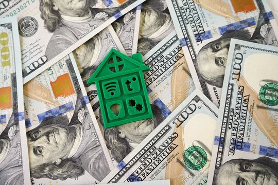 Smart home technology. The figure of a smart house lies on dollars. The concept of investing in modern technologies