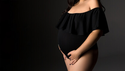 Pregnant woman in black lingerie on a black background.