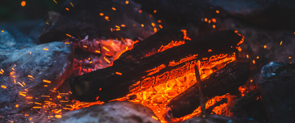 Vivid smoldered firewoods burned in fire closeup. Atmospheric background with orange flame of...