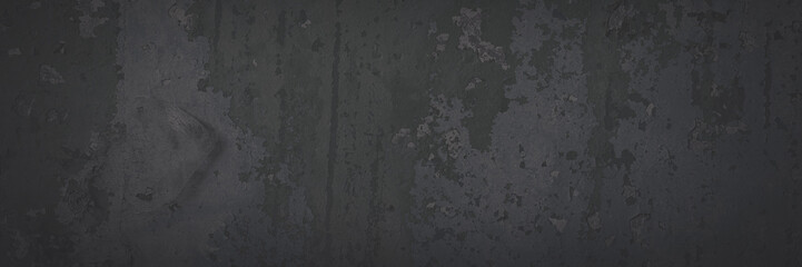 Dark wide panoramic background. Peeling paint on a concrete wall. Faded dark texture of old cracked flaking paint. Weathered rough painted surface with patterns of cracks. Shaded background for design