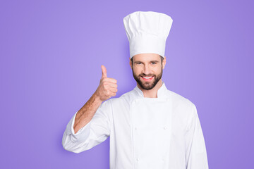 Portrait of cheerful joyful chef cook with stubble in beret, white outfit showing thumb up, approve...