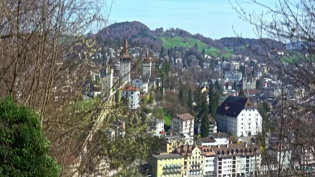 Aerial view of City of Luzern with city wall and tower of the old town seen from cable car of local mountain G&uuml;tsch on a sunny spring day. Movie shot March 22nd, 2023, Lucerne, Switzerland.