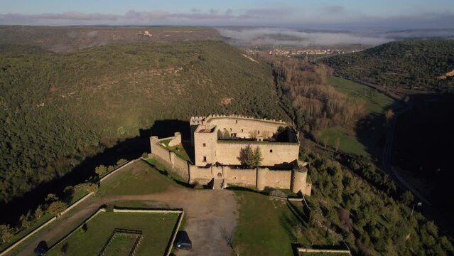 Aerial dolly in towards medieval castle on hilltop in Pedraza Spanish village at sunrise