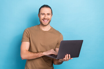 Photo of young smiling optimistic cheerful youtube video maker guy hold netbook remote freelance job promo isolated on blue color background