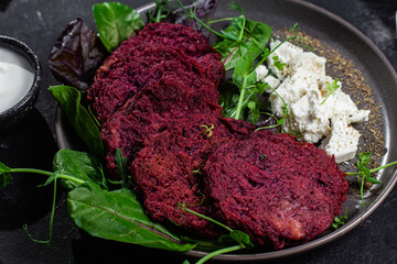 Beetroot pancakes with feta and herbs on a dark plate