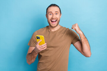 Photo of excited funny winner lottery online gambling phone internet parimatch fist up celebrate million jackpot isolated on blue color background