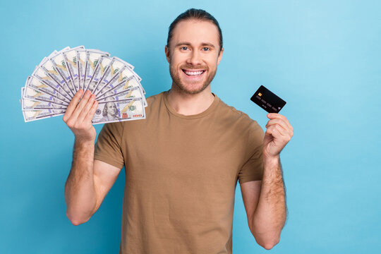 Photo image of cheerful positive good mood promoter man banker hold plastic card cashback money dollars cash isolated on blue color background
