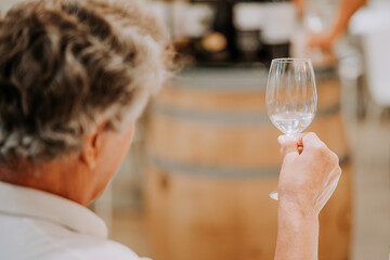 Mature man drinks white wine in glass,tasting winery production in store factory