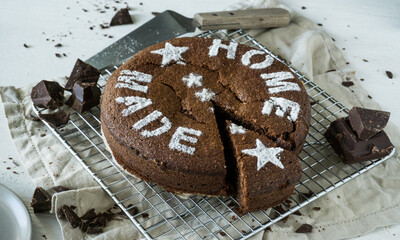 Flourless chocolate almond layer cake with powedered sugar decoration on top white wooden background close up selective focus