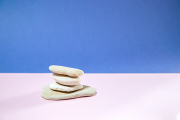 stack of white stones on blue and soft pink background, space for text, podium for beauty poducts