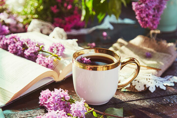 Aesthetic cottage core lifestyle - coffee break with cup of coffee, book and lilac flowers....