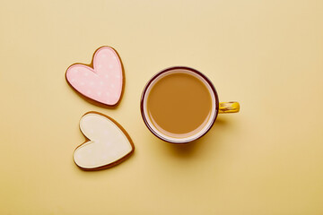 Aesthetics coffee cup and shape heart cookies. Spring card with baked glazed cookies on yellow background. Breakfast, feminine concept. Womens Day, Mothers Day